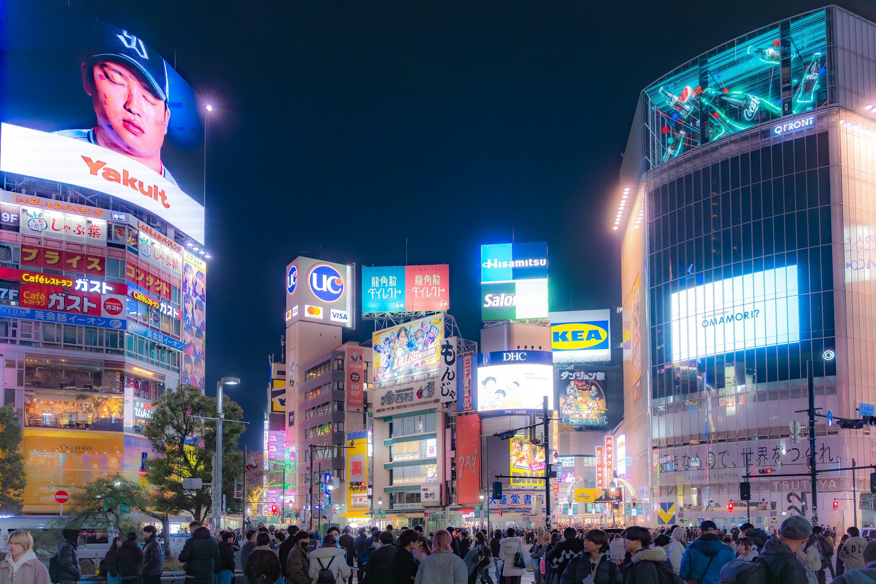 Vista noturna de Shibuya, iluminada por néon e painéis urbanos.